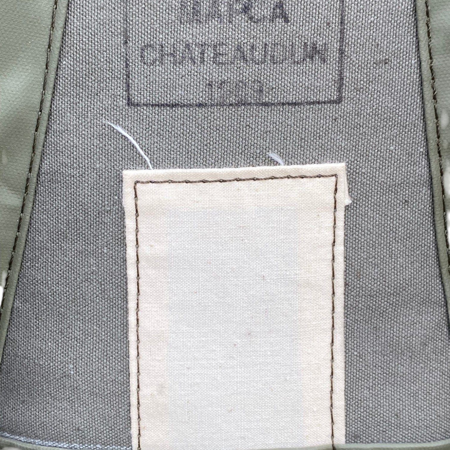 Sac à dos militaire F1 60L/90L Armée française: étiquette textile beige avec patch à coudre sur tissu gris, logo discret en haut.
