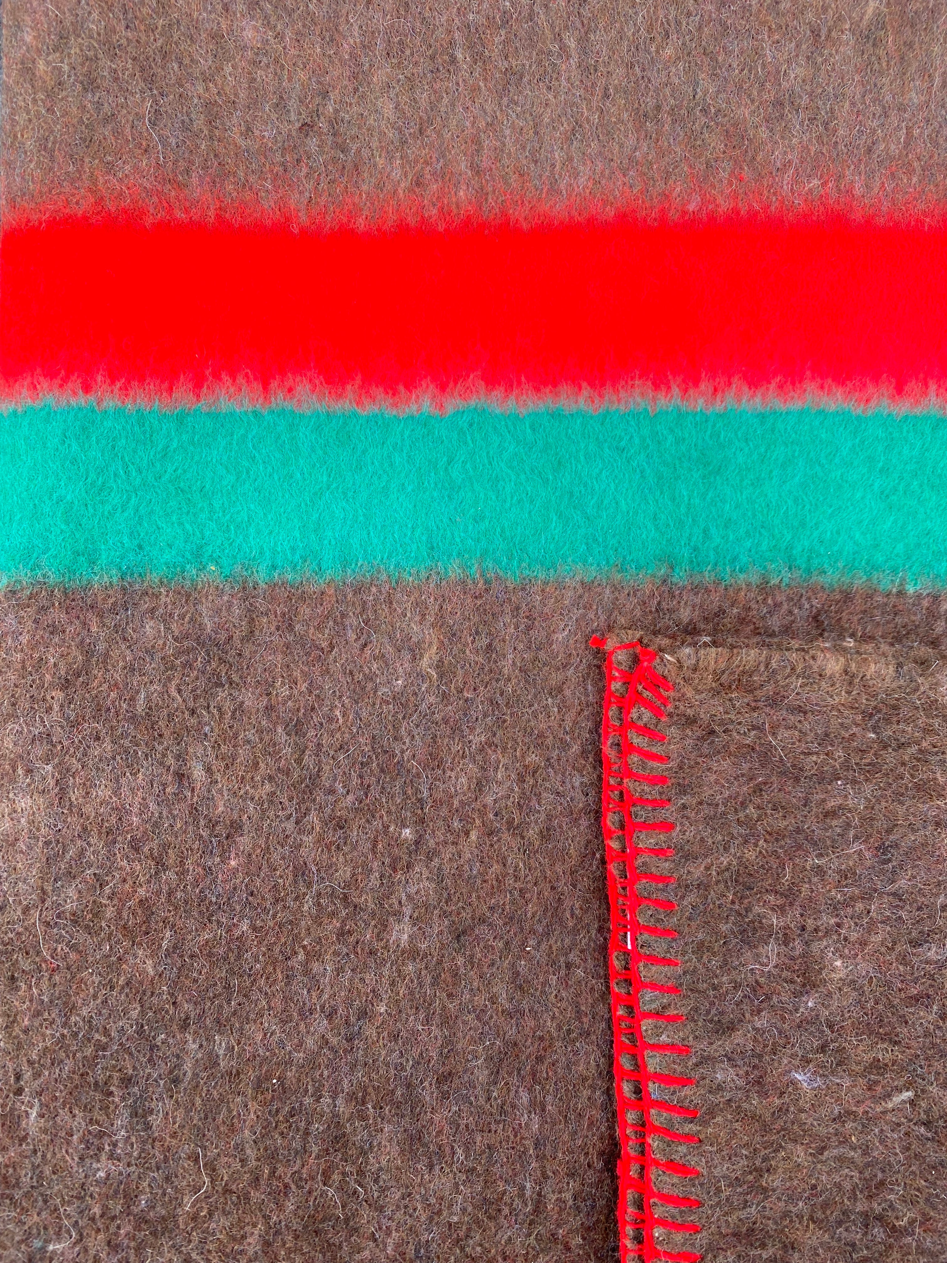 Couverture militaire en laine: gros plan de tissu brun avec une bande rouge et une bande verte, fermeture éclair rouge verticale.