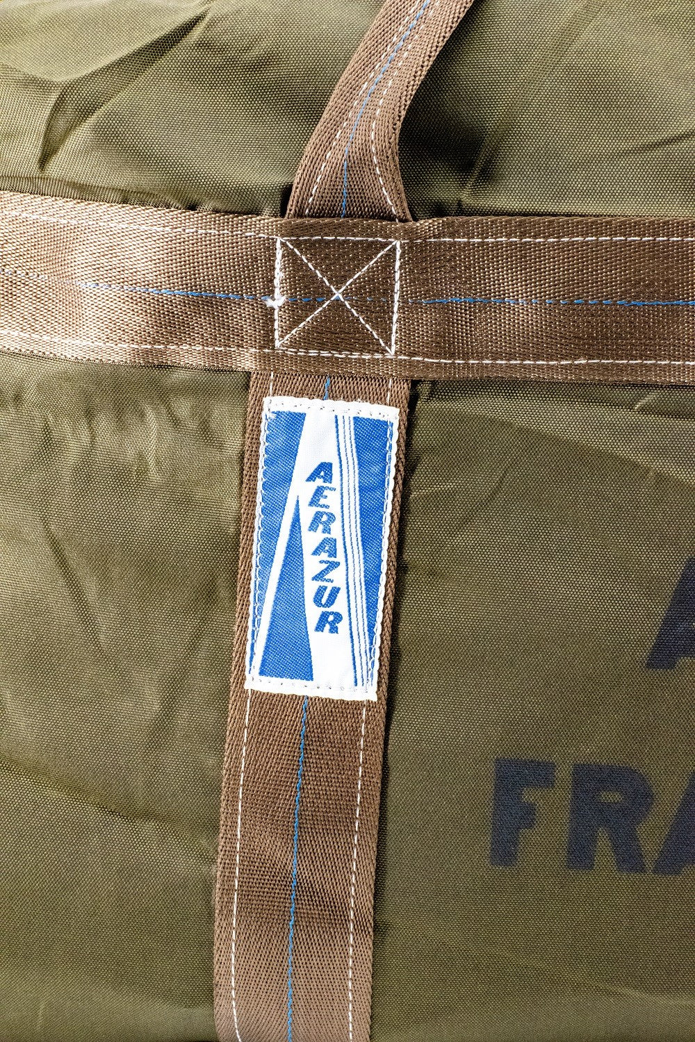 Sac TAP militaire des troupes aéroportées françaises: close-up d’une sangle et étiquette bleue Aerazur sur fond kaki.