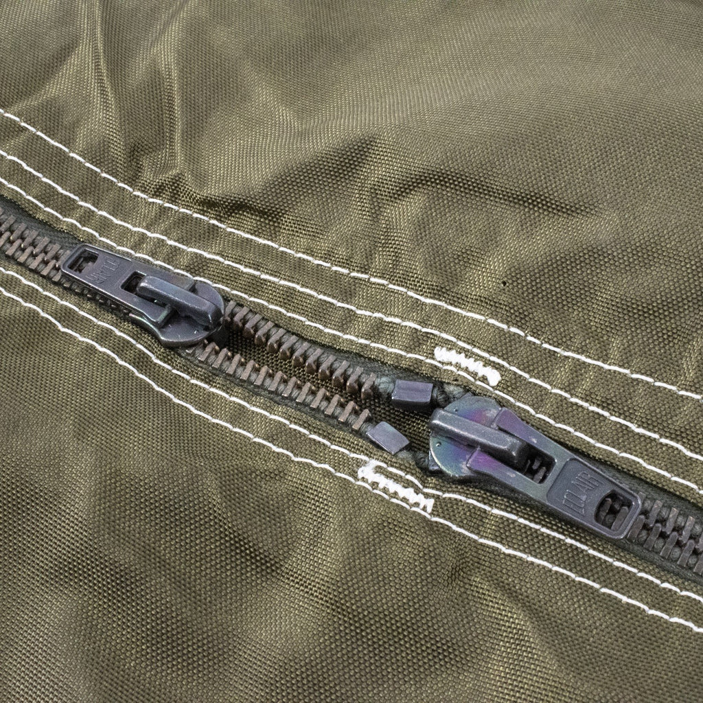 Couture et fermeture éclair doubles sur tissu olive: fermeture éclair centrale avec deux curseurs et drawer, sur sac militaire TAP.