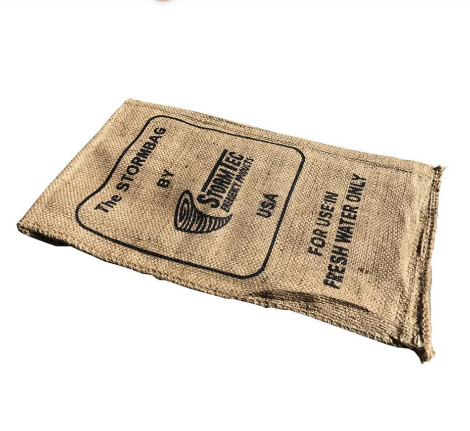 Sac anti-inondation en tissu beige, plié, avec logo et texte Stormbag – sac haute performance pour protéger du feu.