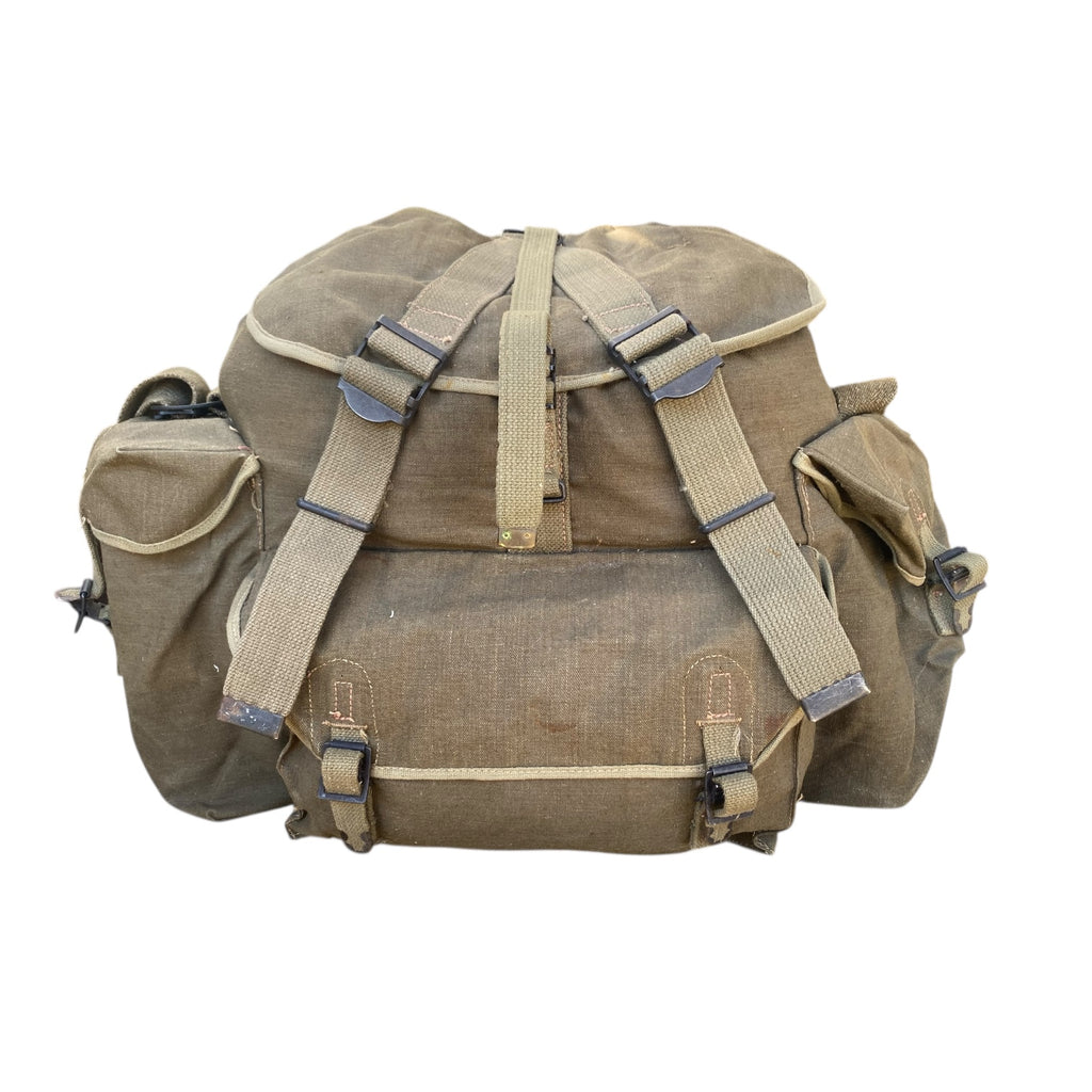 Sac à dos militaire beige, avec bretelles et pochettes latérales, aspect rugged et fixation métallique. Sac TAP 50 armée française Algérie (guerre).